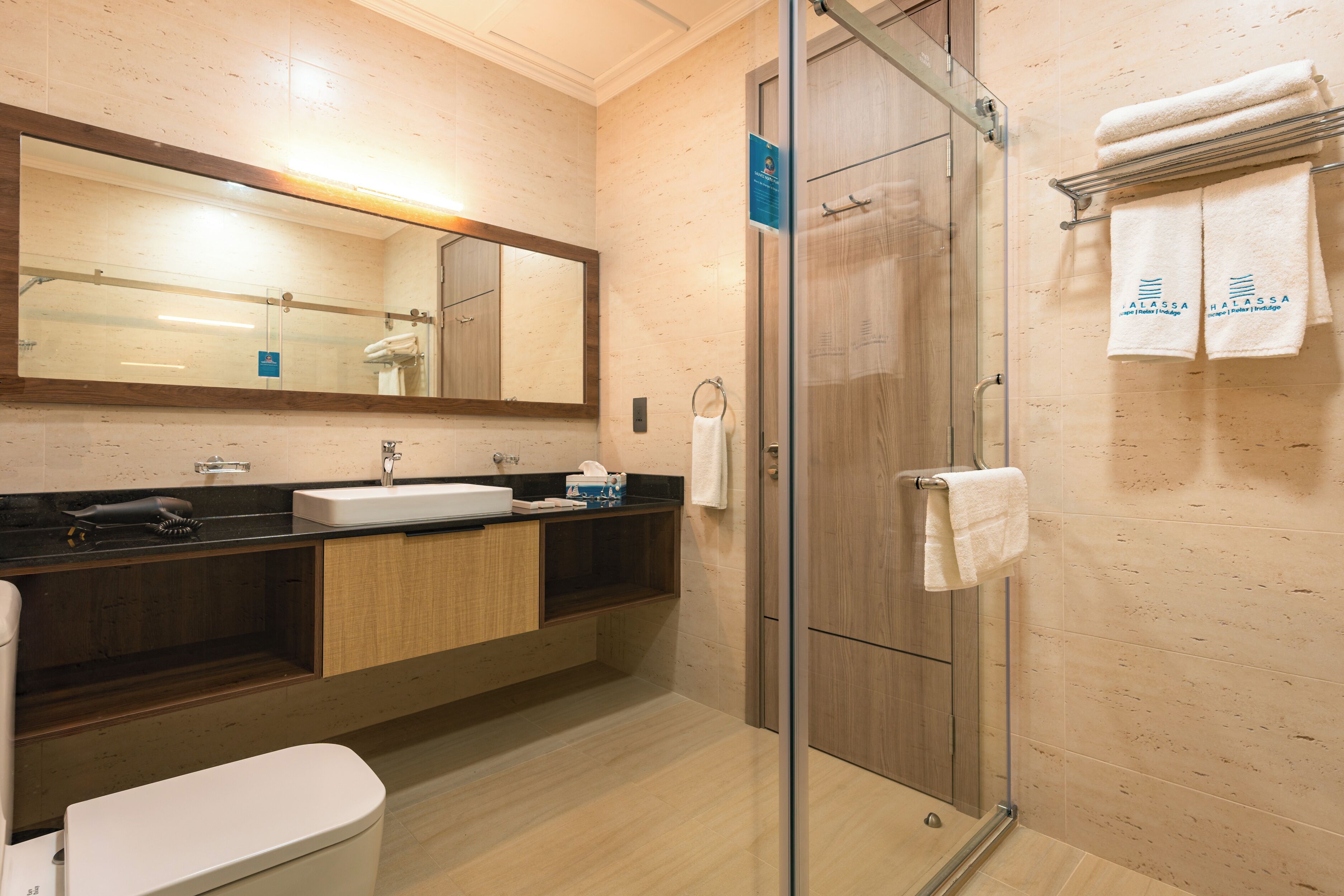 Un baño moderno con cabina de ducha de vidrio, un lavamanos con espejo y un inodoro.