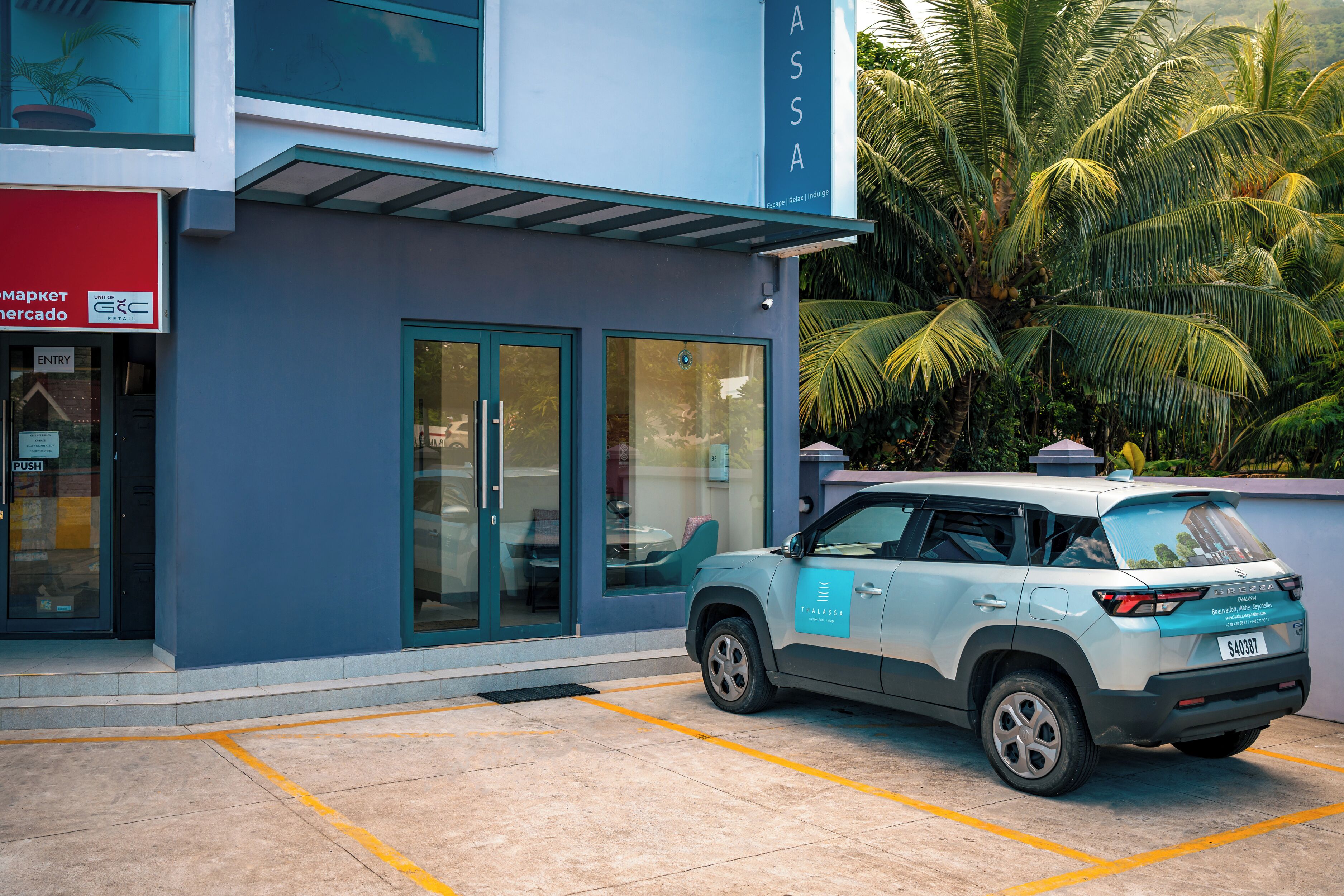 Un edificio moderno con fachada azul, un coche estacionado adelante y un letrero que dice “ASA”.