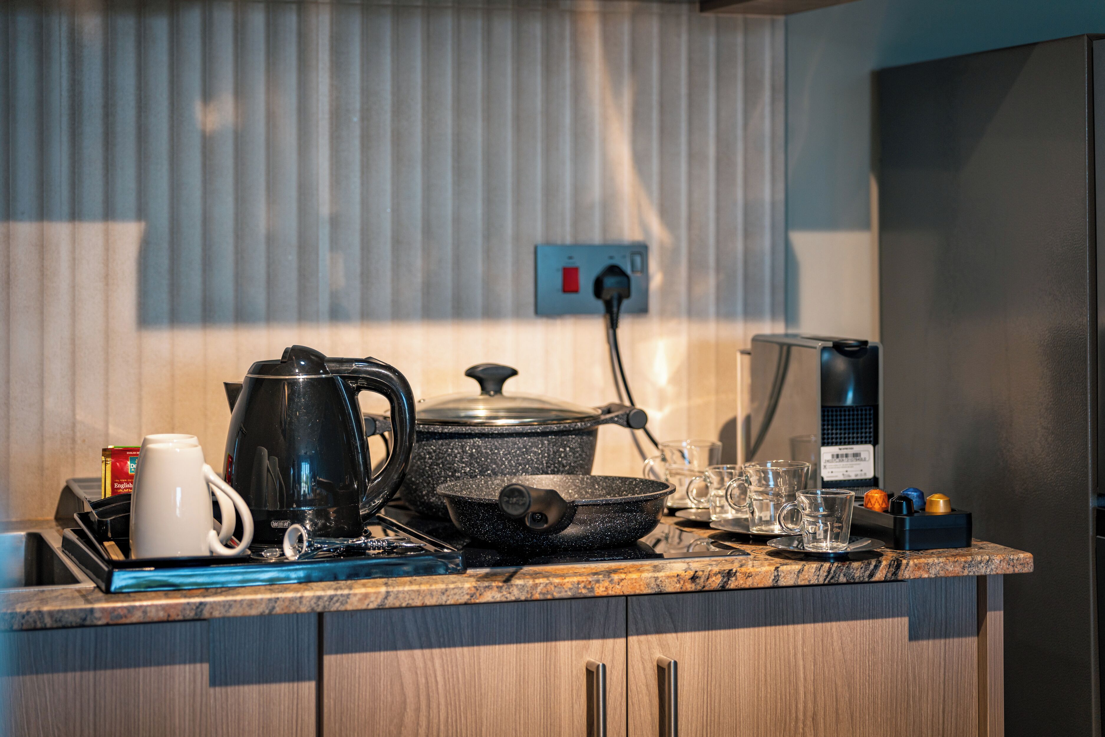 A kitchen counter with a coffee maker, kettle, frying pan, and a microwave.