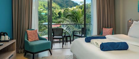 A hotel room with a balcony, a bed, a chair, and a desk.