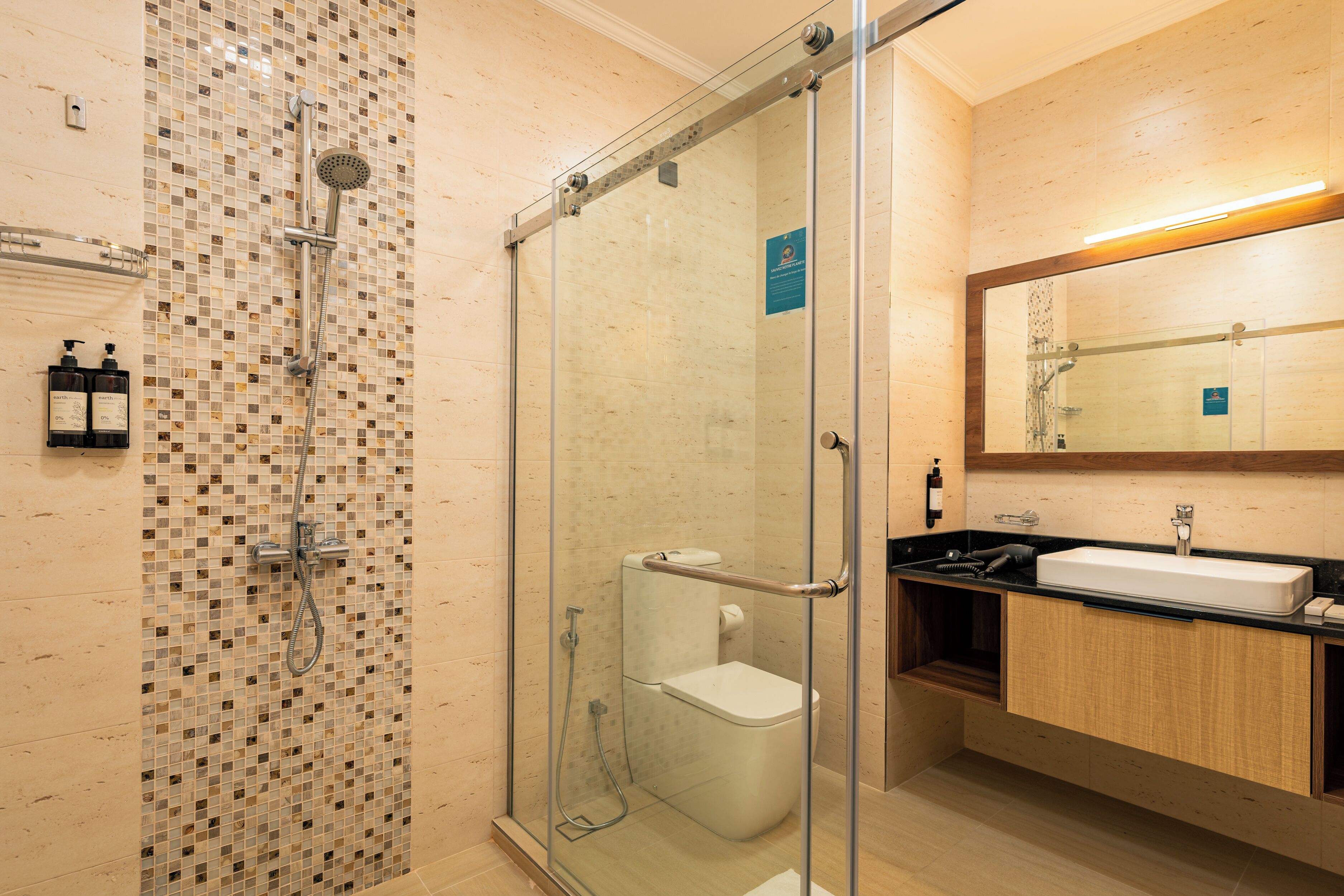 Un baño moderno con ducha de vidrio, inodoro blanco y lavabo con tocador de madera.