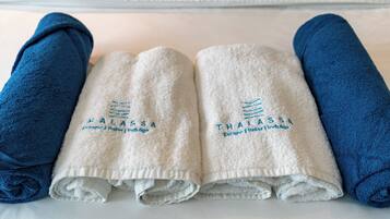 A neatly arranged set of towels on a bed, with two blue towels on the sides and two white towels in the center, each with embroidered text.