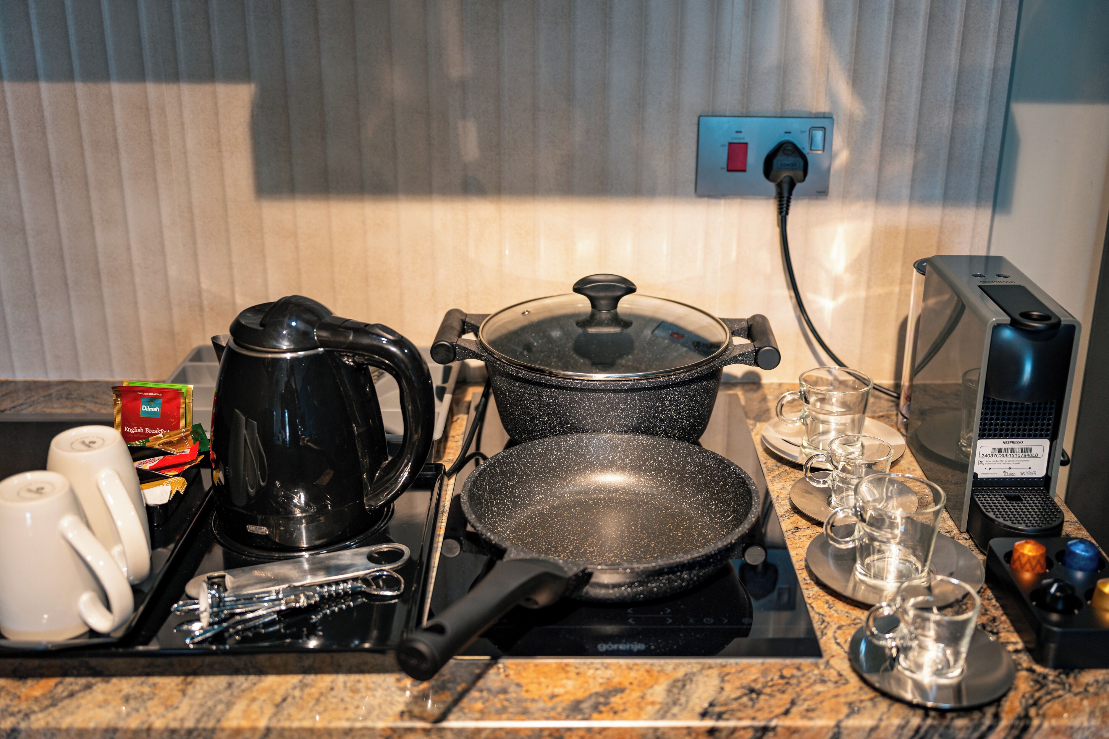 A kitchen counter with a coffee maker, frying pan, and glassware.