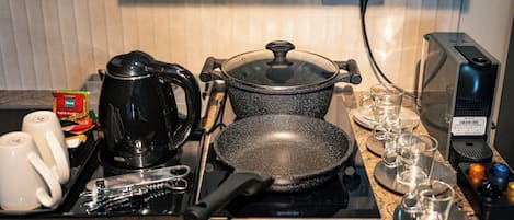 A kitchen counter with a coffee maker, frying pan, and glassware.