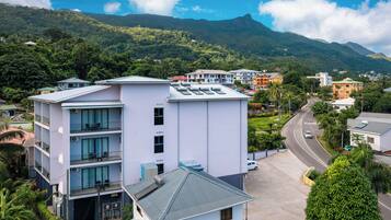 Un hôtel à plusieurs étages doté de balcons, d’un parking et offrant une vue sur la verdure environnante et les montagnes.