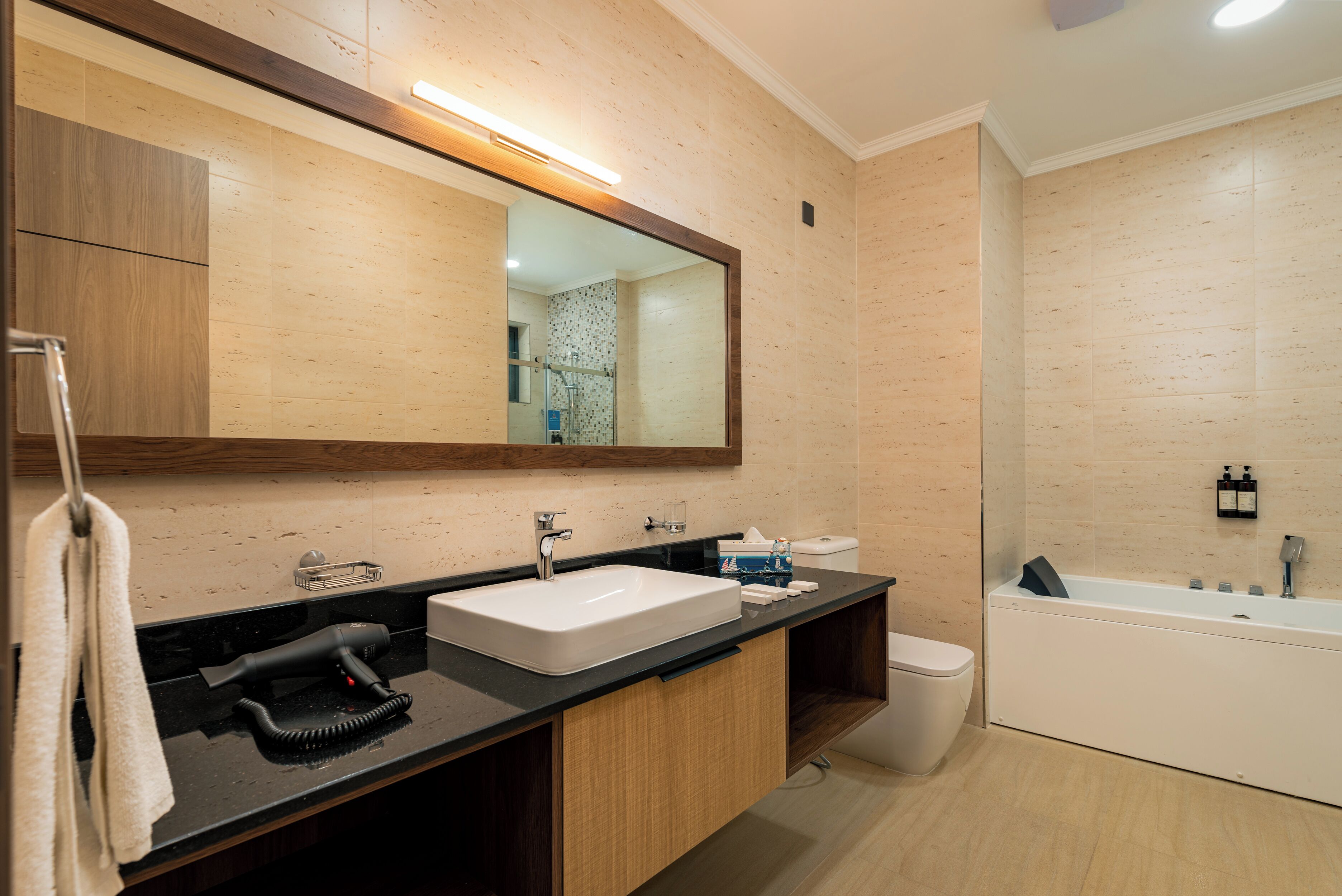 Een moderne badkamer met een grote spiegel, een wastafel, een haardroger en een bad.