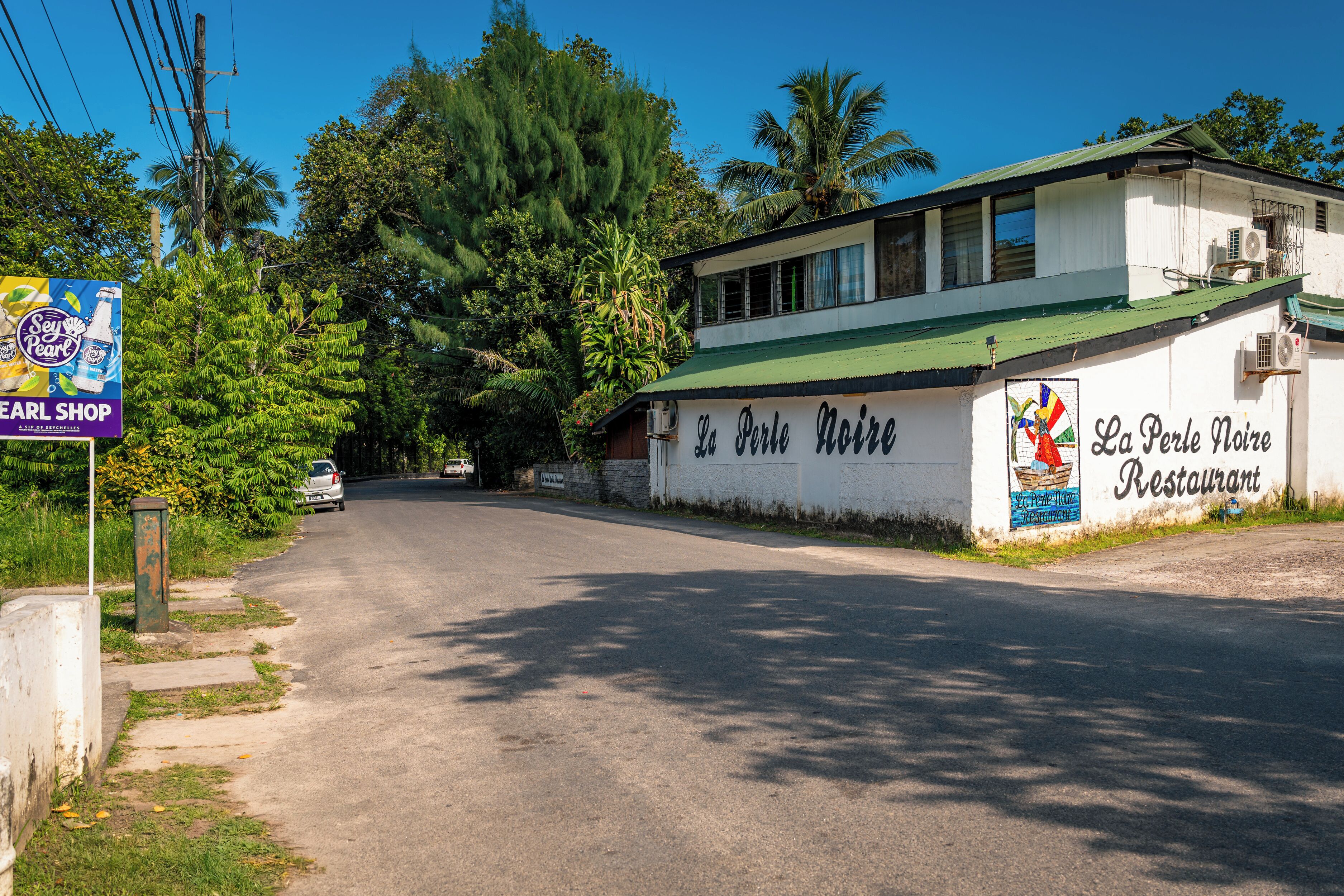 Un bâtiment sur lequel on peut lire l’enseigne « La Perle Noire, restaurant », et à proximité, une autre enseigne indiquant un magasin appelé « Earl Shop ».