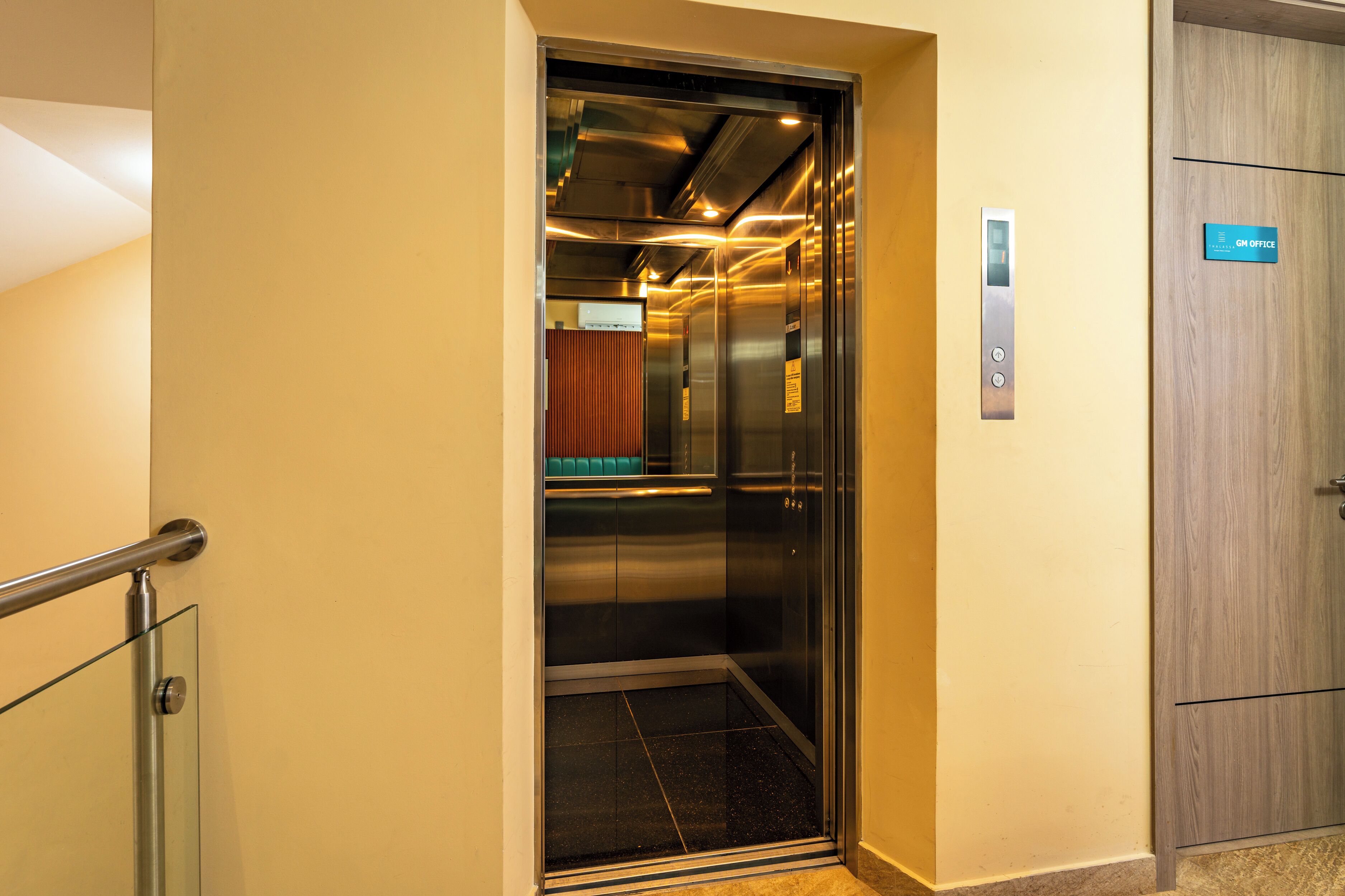 An elevator with a digital display, a control panel, and a sign indicating the direction to the "GH Office".