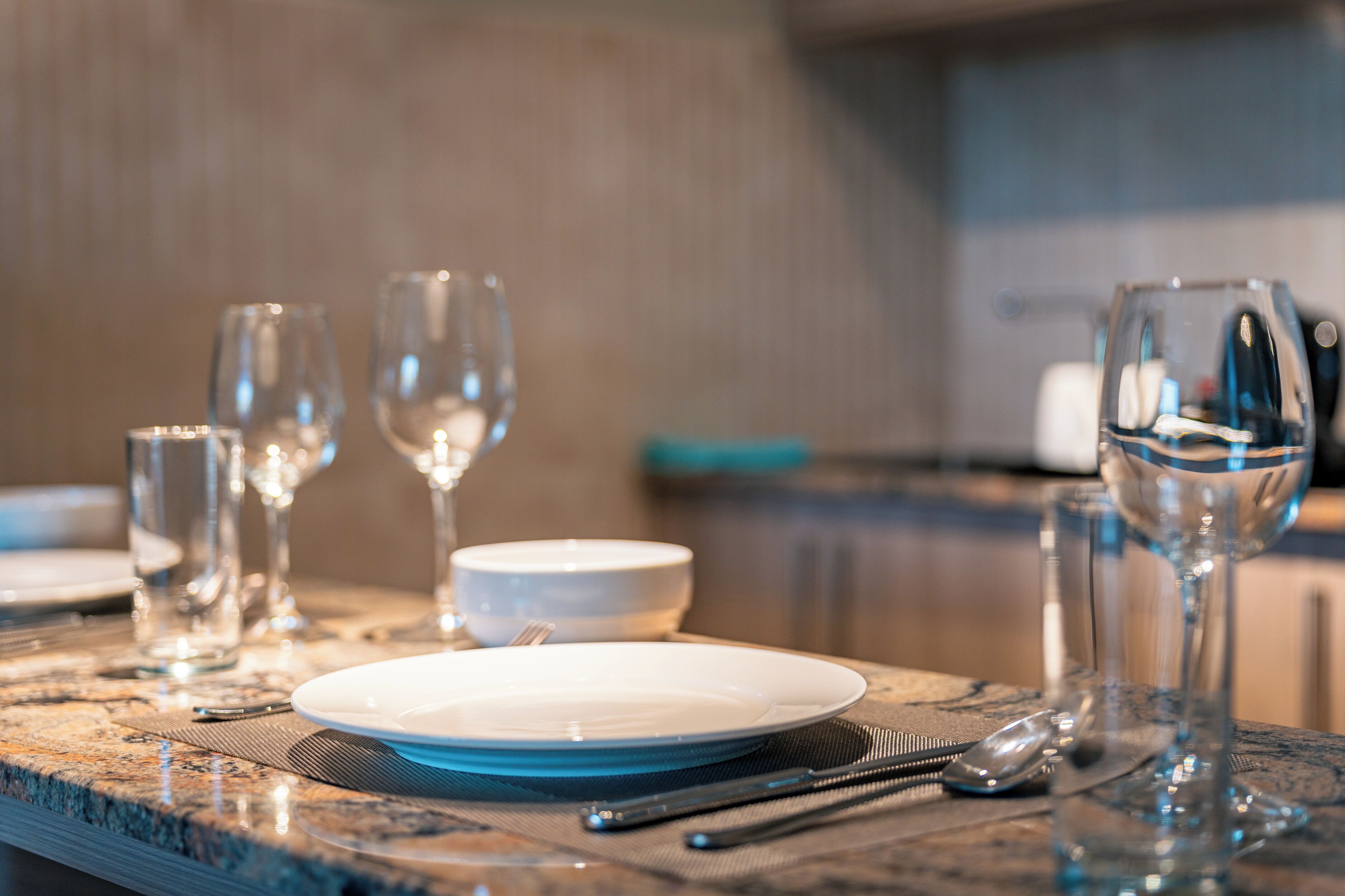 A dining table set with plates, cutlery, and glasses, indicating a prepared meal setting.