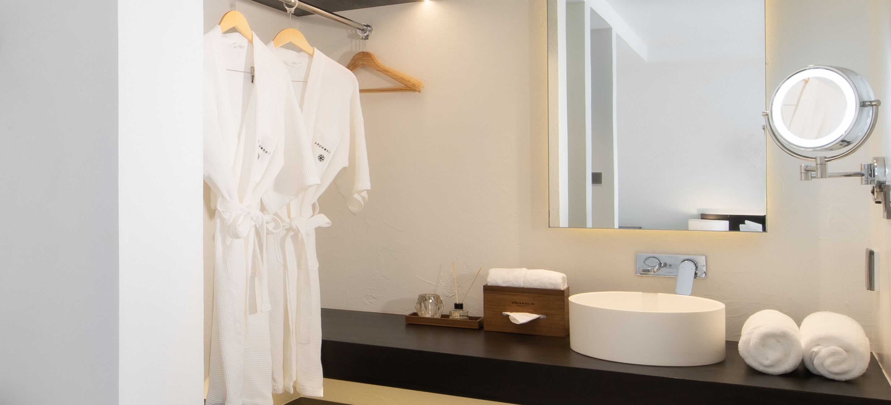 A modern bathroom with a round sink, a mirror, and two towels.