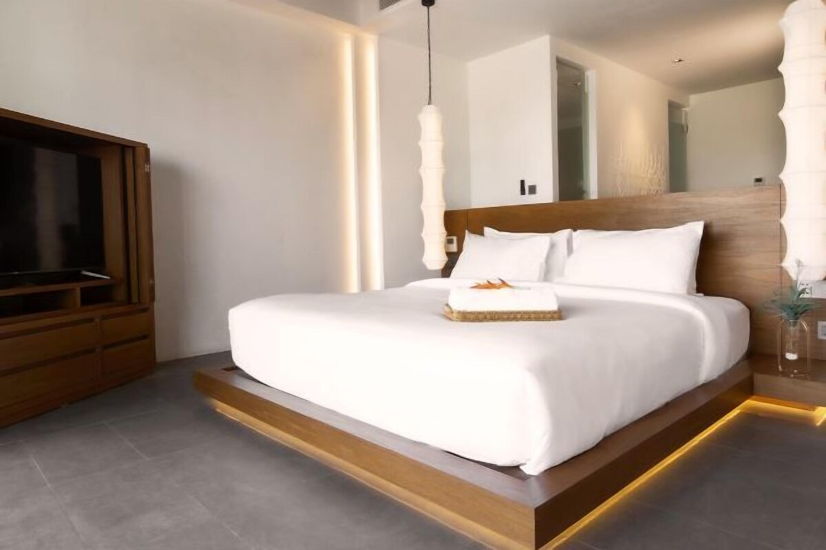 Une chambre à coucher moderne avec un grand lit, un téléviseur à écran plat et une tête de lit en bois.