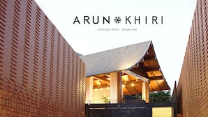 A modern hotel with a distinctive brick facade and a unique architectural design featuring a sloped roof and large windows. - Arun Khiri Chiang Mai Hotel (Chiang Mai)