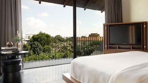 A hotel room with a large bed, a television, and a view of greenery and buildings. - Arun Khiri Chiang Mai Hotel (Chiang Mai)