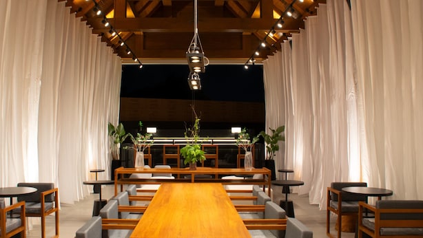 A spacious dining area with a long wooden table, multiple chairs, and potted plants. - Arun Khiri Chiang Mai Hotel (Chiang Mai)
