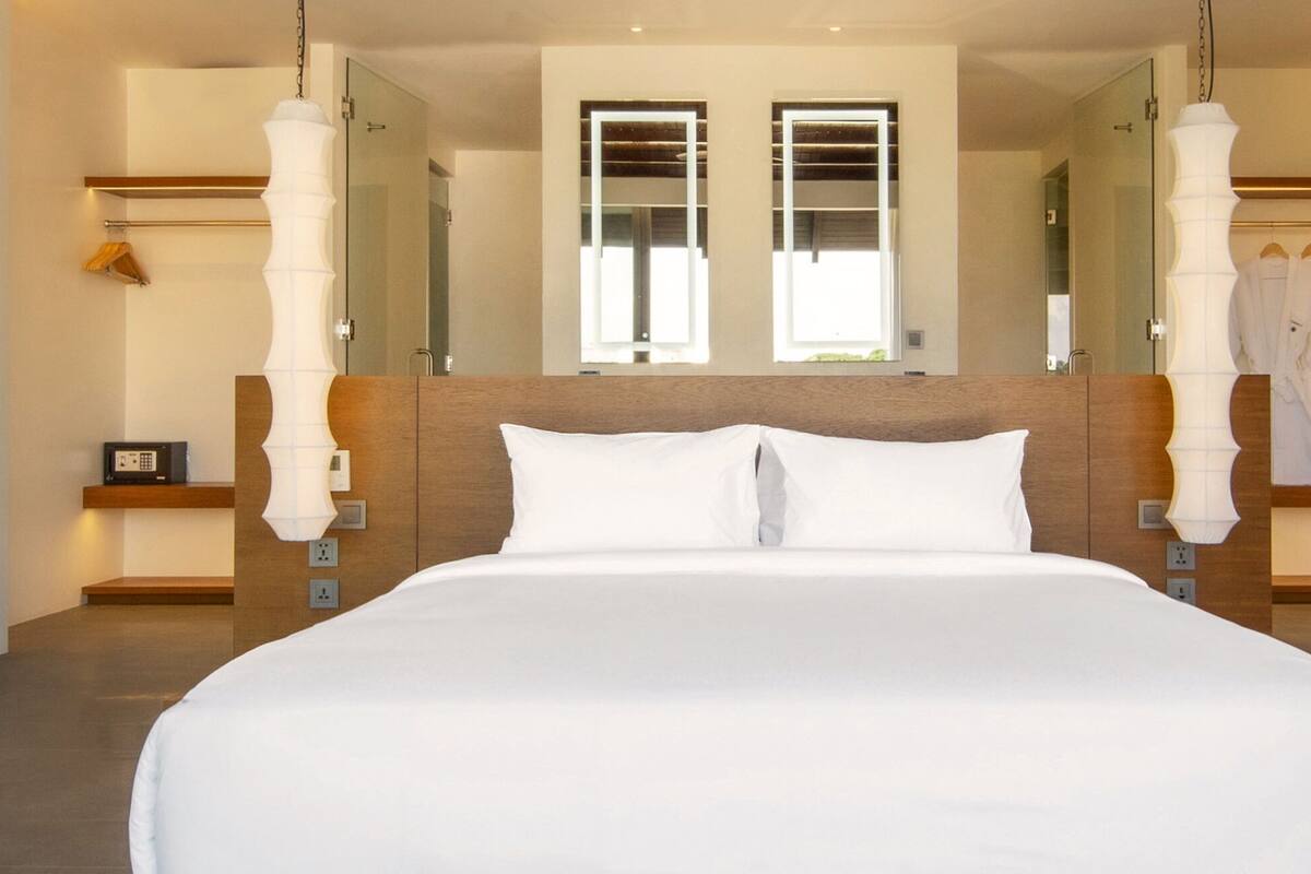 Una cama grande con ropa blanca en una habitación de hotel moderna.