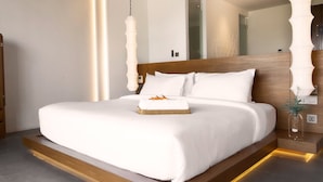 A modern hotel room with a large bed, a wooden nightstand, a TV, and a mirror. - Arun Khiri Chiang Mai Hotel (Chiang Mai)