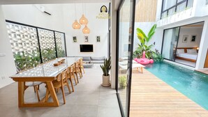 Quarto de hotel moderno com área de refeições, piscina e quarto de dormir.
