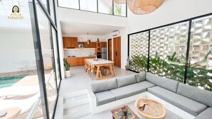 Uma cozinha moderna com armários de madeira, uma área de jantar com mesa de mármore e um sofá cinzento.