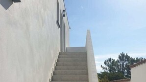 A staircase leading up to a building with a plain exterior and a clear sky in the background.
