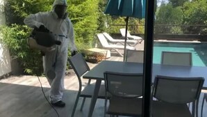 A person in protective gear near a pool area with outdoor seating and a table.