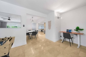 A modern interior with a dining area, a workspace, and a foosball table.