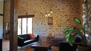 A stone-walled room with a sofa, a coffee table, and a potted plant.