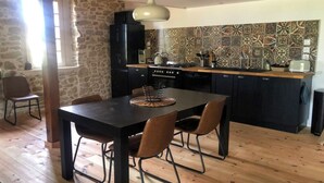 A kitchen with a stone wall, a tiled backsplash, and wooden flooring.