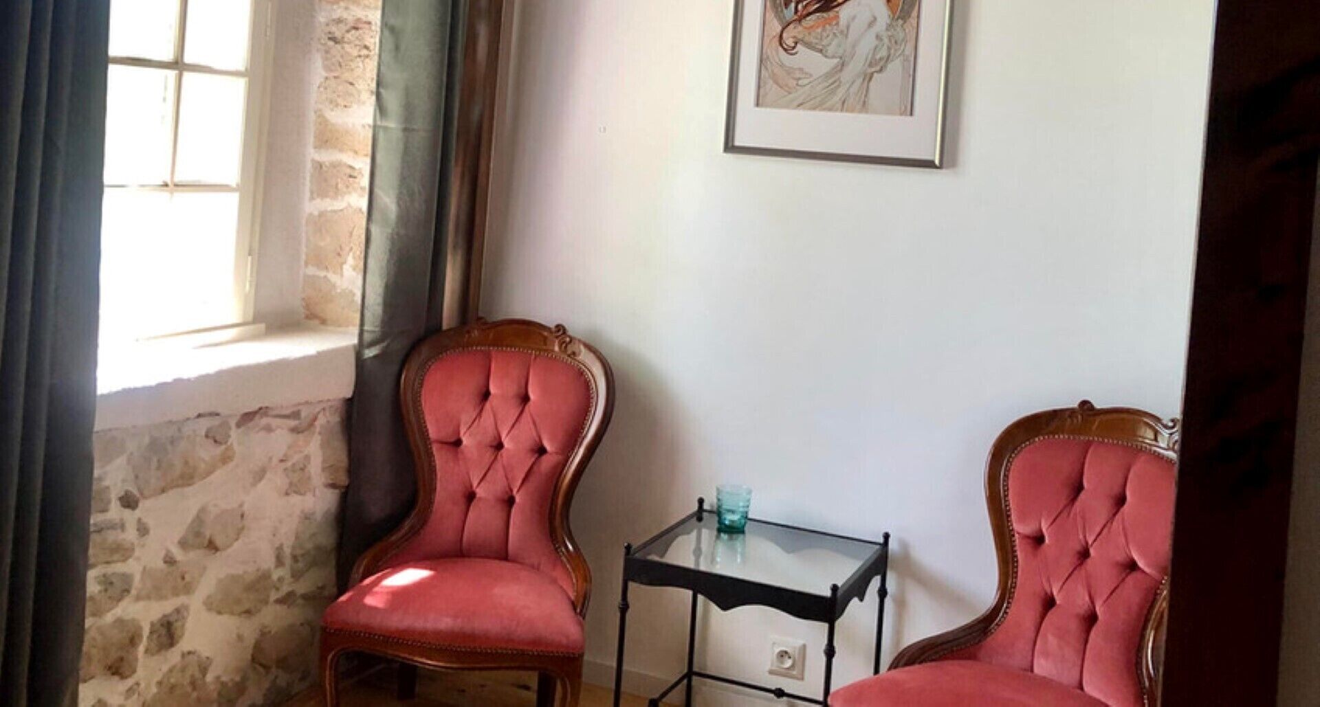 Una habitación con dos sillones tapizados, una mesita y un ventanal con cortinas.