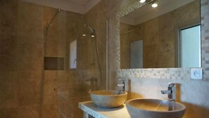 A bathroom with two large, round, beige stone sinks, a glass-enclosed shower, and a tiled backsplash. - Villa Panoramique Piscine Chauffee 4 CH +4 SDB (SARI SOLENZARA)