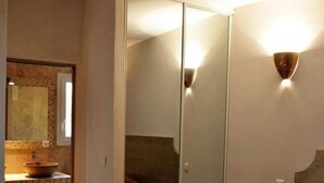 A bedroom with a large mirror, a bedside table, and a brown bedspread. - Villa Panoramique Piscine Chauffee 4 CH +4 SDB (SARI SOLENZARA)