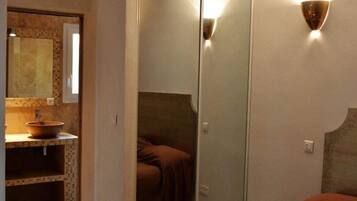Un dormitorio con un espejo grande, una mesita de noche y una colcha marrón.