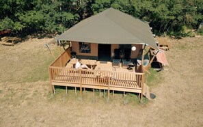 A wooden deck with outdoor seating and a covered area. - Glamping Lodge Monet | Domaine du Cammazet | Pool| Comfort | Nature (Lapenne)