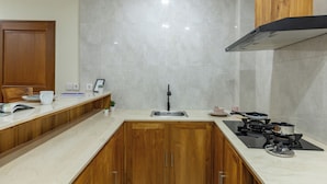 A kitchen with a wooden countertop, a sink, a stove, and cabinets. - Cove Griya Elite (Denpasar)