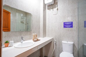 A modern bathroom with a sink, mirror, shower, and toilet. - Cove Griya Elite (Denpasar)