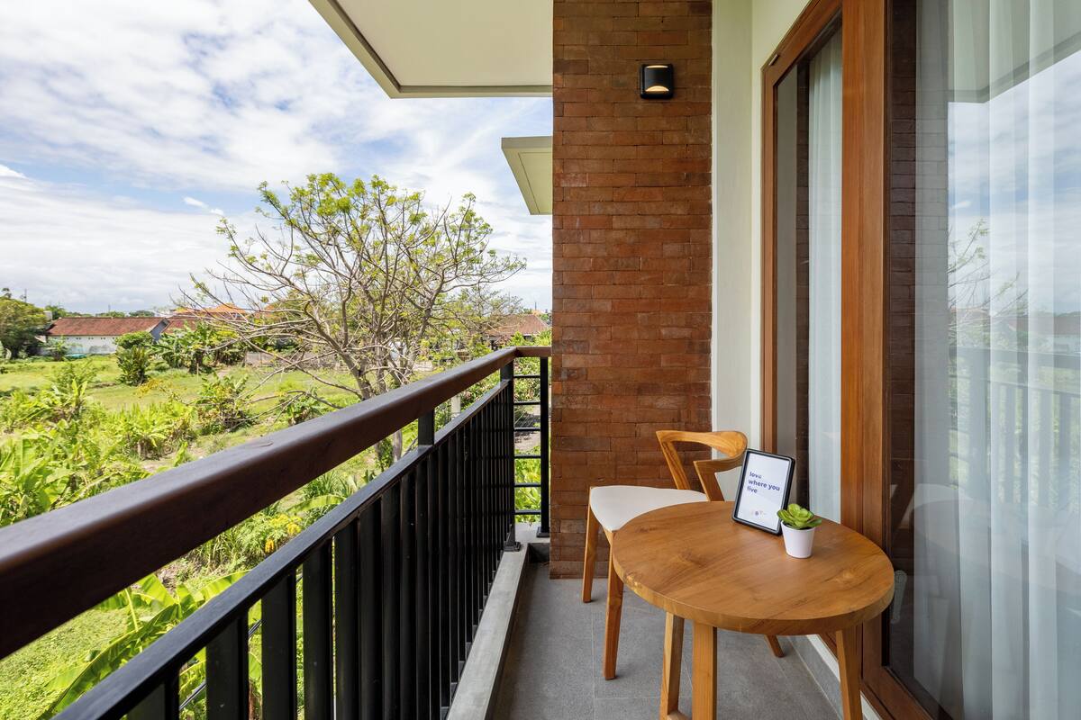A balcony with a wooden table and chairs, a potted plant, and a framed sign.