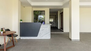 A reception area with a marble counter, a small table with chairs, and a view into the kitchen. - Cove Griya Elite (Denpasar)