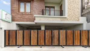 A modern two-story building with a brick facade, a balcony with a black railing, and a decorative wall. - Cove Griya Elite (Denpasar)