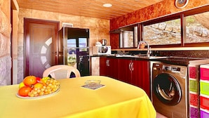 Una cocina con techo de madera, lavadora y una mesa con fruta.