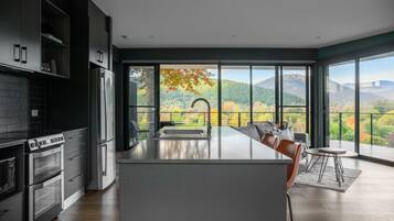 A modern kitchen with a large island, built-in appliances, and a view of a mountainous landscape through large windows.