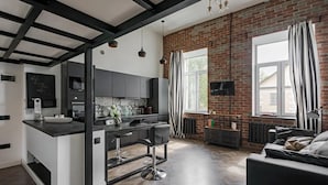 A modern kitchen with a central island, bar stools, and a dining area with a sofa. - Lux apartment in Minsk (Minsk)