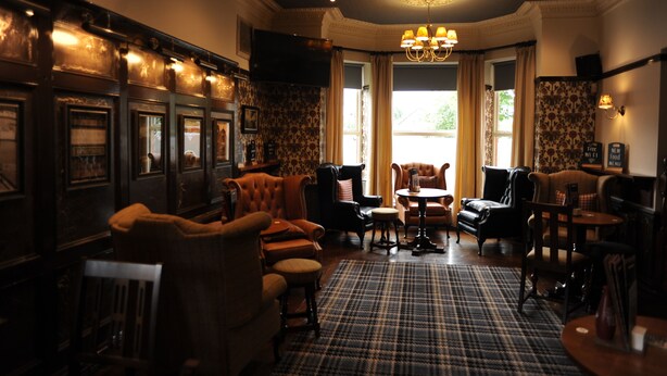 A traditional room with a checkered floor, multiple seating areas, and a large window with curtains. - The Spread Eagle (Manchester)