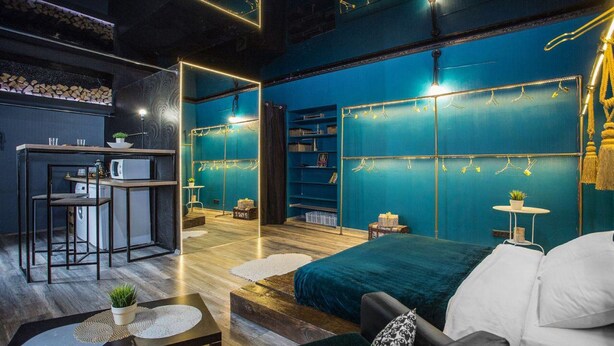 Une chambre moderne avec un mur d’accent de couleur turquoise, un lit, un bureau avec une chaise et une bibliothèque.