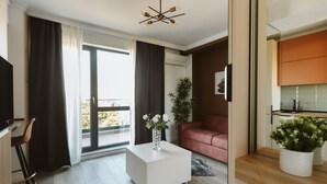 A modern living room with a white coffee table, a red sofa, and a large window with curtains. - Dec Apartments (Bucharest)