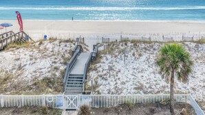 Ein Strand mit einer Holzpromenade, die zu einem Restaurant direkt am Strand führt.