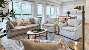 A spacious living room with a sofa, armchairs, a coffee table, and a dining area with a table and chairs. - Lakefront, Private Hot Tub, By Downtown Landing | Mini Pearl (Branson)