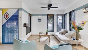 A modern living room with a sofa, two armchairs, a coffee table, and a ceiling fan.