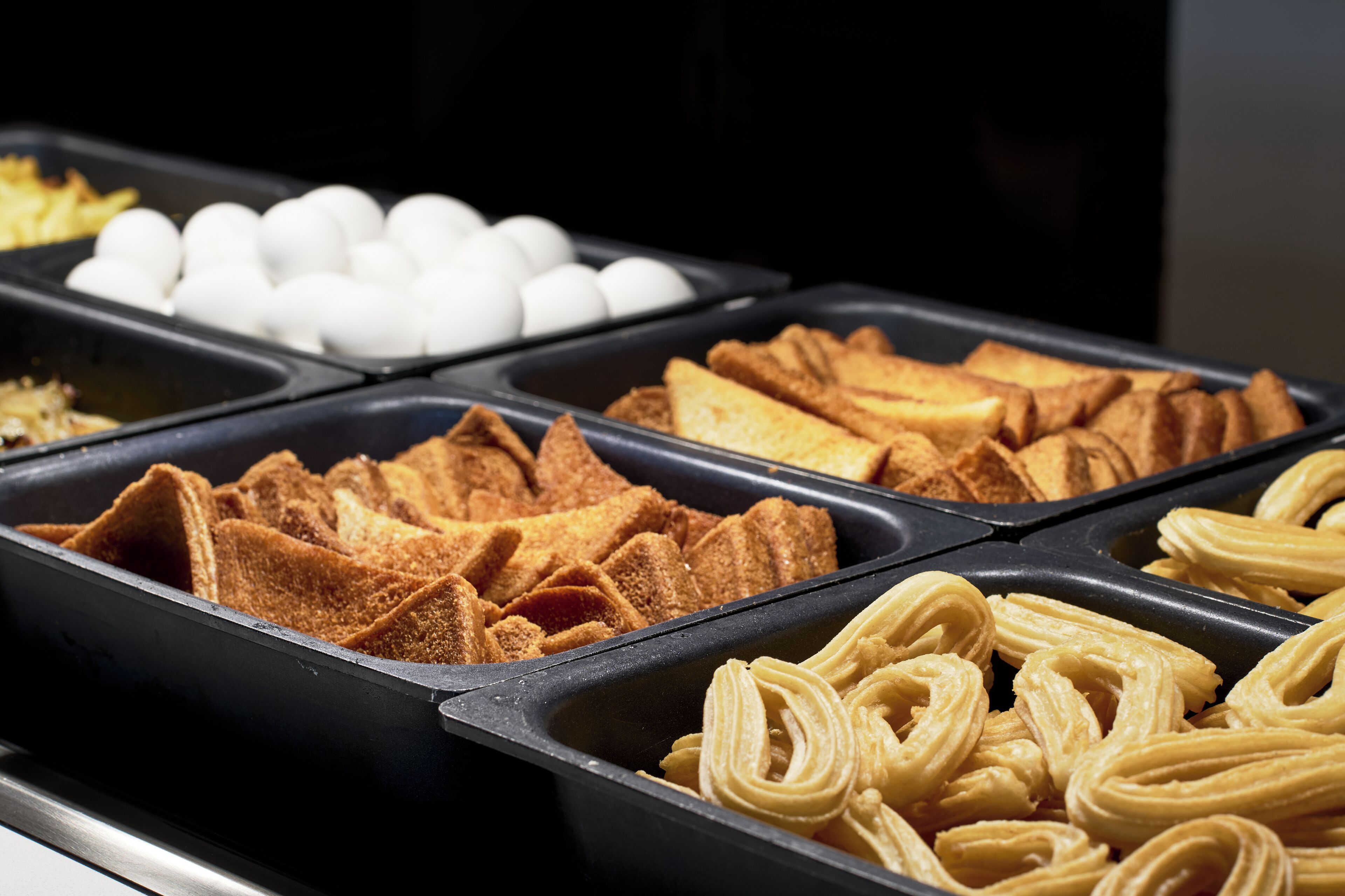 Buffet amb diferents plats, incloent pa, ous i pastissos.