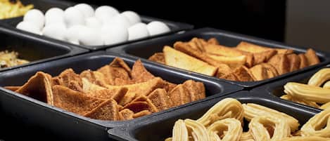 Un buffet proposant une variété d’aliments, notamment du pain, des œufs et des viennoiseries.