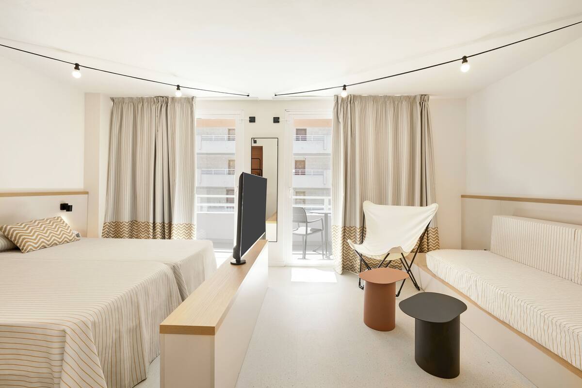 A hotel room with two beds, a TV, a chair, and a small table.