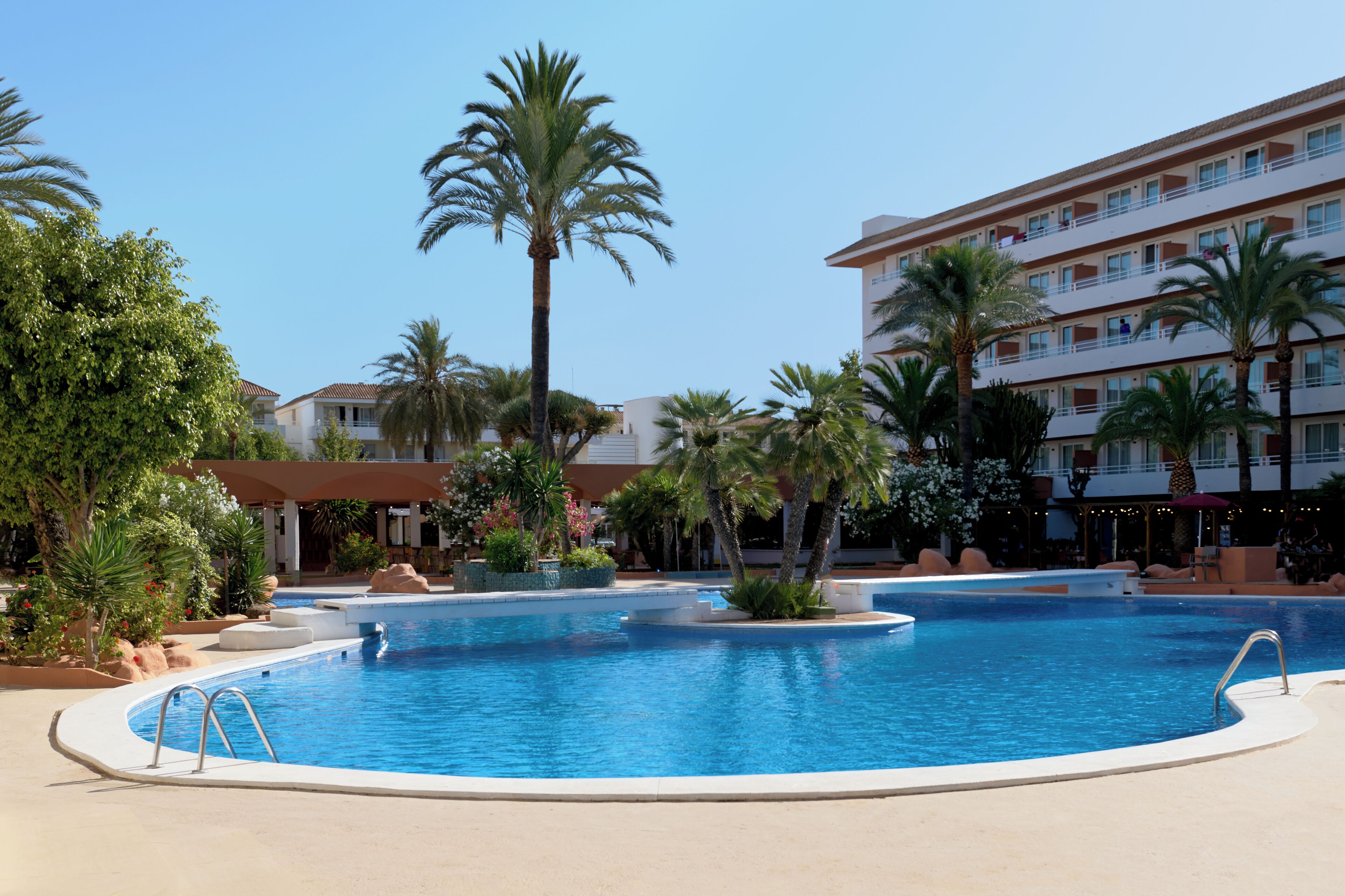 Una gran piscina al aire libre rodeada de palmeras y un edificio de hotel.